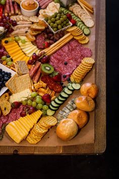 a wooden table topped with lots of different types of cheeses and crackers on top of it