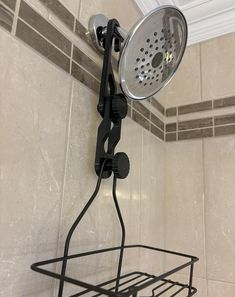 the shower head is attached to the wall above the basket in the shower stall, which also has an overhead strainer