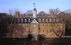 an old brick building with a clock tower on top and trees in the foreground