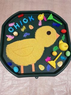 a child's play tray with various toys and letters on it that spell out chick