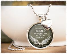 a necklace with a heart and wings on it sitting in front of a white bowl