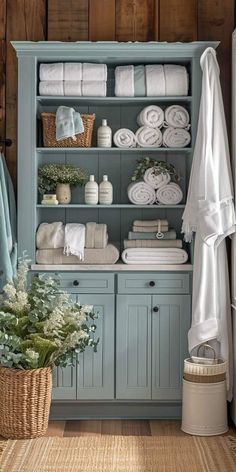 a bathroom with blue cabinets and white towels on top of the shelves in front of it