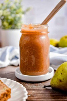 a jar filled with peanut butter sitting on top of a table next to some pears