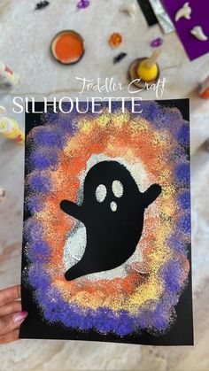 someone holding up a halloween card with a ghost on it