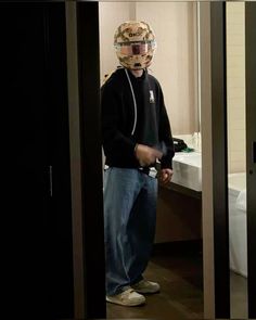 a young man standing in front of a bathroom mirror with a helmet on his head