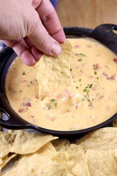 a hand dipping a tortilla chip into a bowl of quesadilla dip