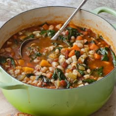 a green pot filled with soup next to slices of bread