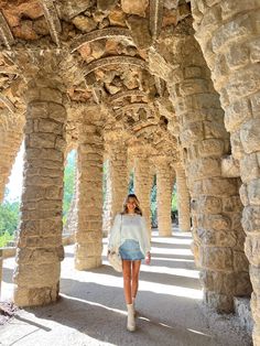 a woman is walking through an old stone structure