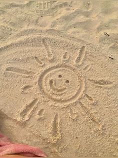 someone's feet in the sand with a sun drawing on it