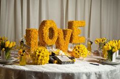 the table is set with yellow flowers and letters that spell out the word love on it