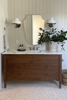 a bathroom with a large mirror and wooden dresser in the corner next to a potted plant