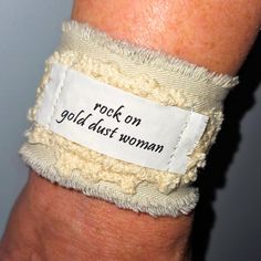 For A Boho Gypsy Wardrobe Hippie Cloth/Fabric Cuff Bracelet Stevie Nicks, Fleetwood Mac Song Lyrics From The Rumors Album "Rock On Gold Dust Woman" A Thoughtful & Personalized Music Lovers Gift! ***Adjustable, Durable & Possibly The Most Comfortable Bracelet You'll Ever Own! Eco Friendly & Sustainable Text Is Heat Set & Water Resistant Cleans With A Wet One Or Machine Wash Upcycled Sandstone Beige Fabric With Gray Backing Accented With Vintage Crochet Frayed Edges Closes With A Vintage Button & Adjustable Wristband For Festivals, Bohemian White Wristband For Festivals, Adjustable Cream Cuff Bracelet Gift, Adjustable Cream Cuff Bracelet As Gift, Adjustable Cream Cuff Bracelet For Gift, Handmade Trendy Cuff Bracelet For Festivals, Trendy Handmade Cuff Bracelet For Festivals, Rock On Gold Dust Woman, Sandstone Beige