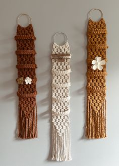 three crocheted wall hangings with flowers on each one and tassels attached to them