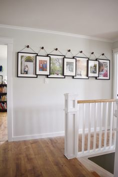 there are pictures hanging on the wall above the bannister in this home's entryway