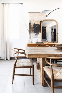 a dining room table with chairs and a mirror