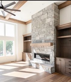 an empty living room with a fireplace and built - in bookshelves