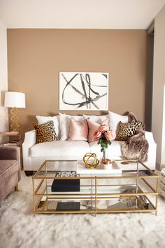 a living room with white couches and leopard print pillows on the back of them