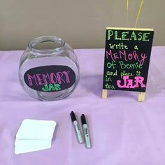 a table topped with a glass vase filled with water and writing next to a chalkboard sign