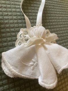 a white cloth ornament with a bow on it's side sitting on a bed