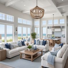 a living room filled with furniture and large windows next to the ocean in front of it