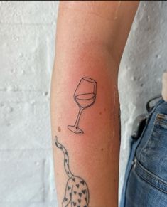 a person with a tattoo on their arm holding a glass of wine in one hand