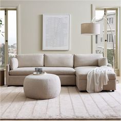 a living room with a large sectional couch and ottoman in the middle, along with a white rug on the floor