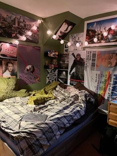 an unmade bed in a room with posters on the wall and lights above it