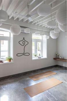 two yoga mats are on the floor in front of three windows with paper lanterns hanging from them