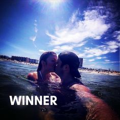 two people are kissing in the water on a sunny day with blue skies and white clouds