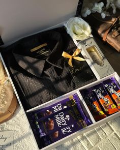 an assortment of chocolates and candy bars in a box on a white tablecloth