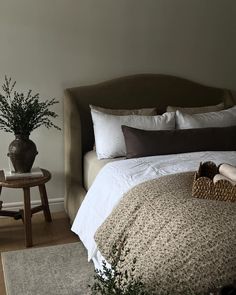 a bedroom with a bed, chair and potted plant