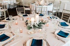 the table is set with white and blue linens, silverware, and candles