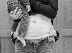 a black and white photo of a woman holding a baby in her lap while wearing jeans