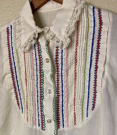 Classic 1970's hand embroidered white blouse with bib detail.  Garment Measurements: Size: Unmarked Pit to Pit: 17" Length: 23" Arm Length: 21" *items may come with minor flaws due to pre-loved wear. we are advocates of buying used and hope you can appreciate this garment and its character. items are pre-handwashed/de-pilled/mended if needed and any major flaws will try to be noted. Please message for additional measurements if needed.  xo Lauren White Embroidered Blouse With Peter Pan Collar, Traditional White Blouse With Buttons, Retro White Embroidered Blouse, Vintage White Blouse With Boho Collar, White Embroidered Vintage Blouse, 70s Blouse, Womens Blouses, White Button Down, Blouse White