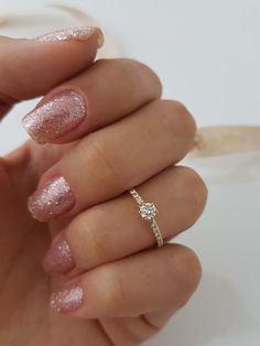 a woman's hand with pink and white nail polish holding a diamond engagement ring