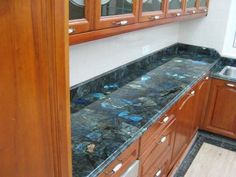 a kitchen with wooden cabinets and marble counter tops