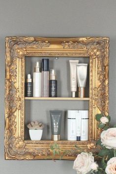 an ornate gold framed shelf with various skin care products and flowers in front of it