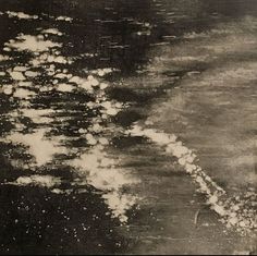 black and white photograph of water with clouds in the sky above it, taken from an airplane