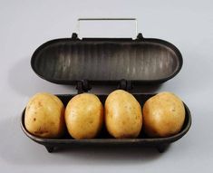 four potatoes in a black container on a white surface