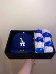 a baseball cap and roses are in a box with the dodgers hat on top of it