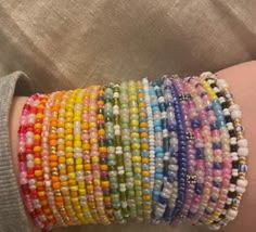 a woman's arm is covered with bracelets made out of beads and glass beads