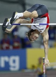 a man is high in the air while jumping over an obstacle bar on a track