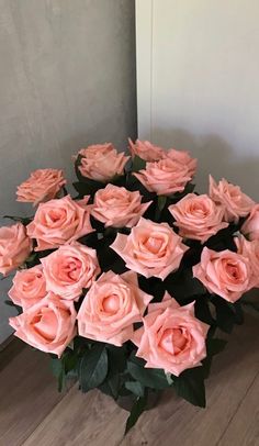 a vase filled with pink roses on top of a wooden floor