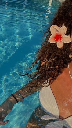 a woman is floating in the water with her hair blowing back and flowers on her head