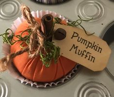 a pumpkin with a sign on it sitting in a cupcake liners holder that says pumpkin muffin