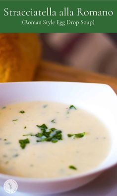 a close up of a bowl of soup on a table with bread in the background