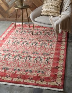 a red rug with an ornate design on the front and back sides, in a living room