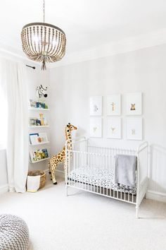 a baby's room with a white crib and a giraffe in the corner