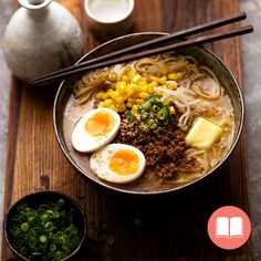 a bowl of ramen with boiled eggs, meat and vegetables on a wooden table