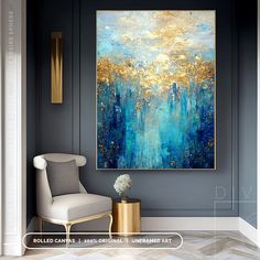 an abstract painting hangs on the wall above a white chair and gold vase in front of it